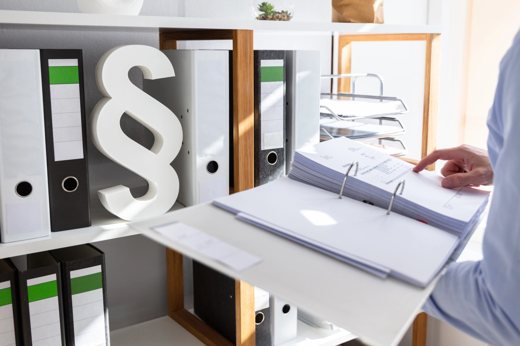 Mann steht im Büro und öffnet Ordner, Klausel im Regal im Hintergrund