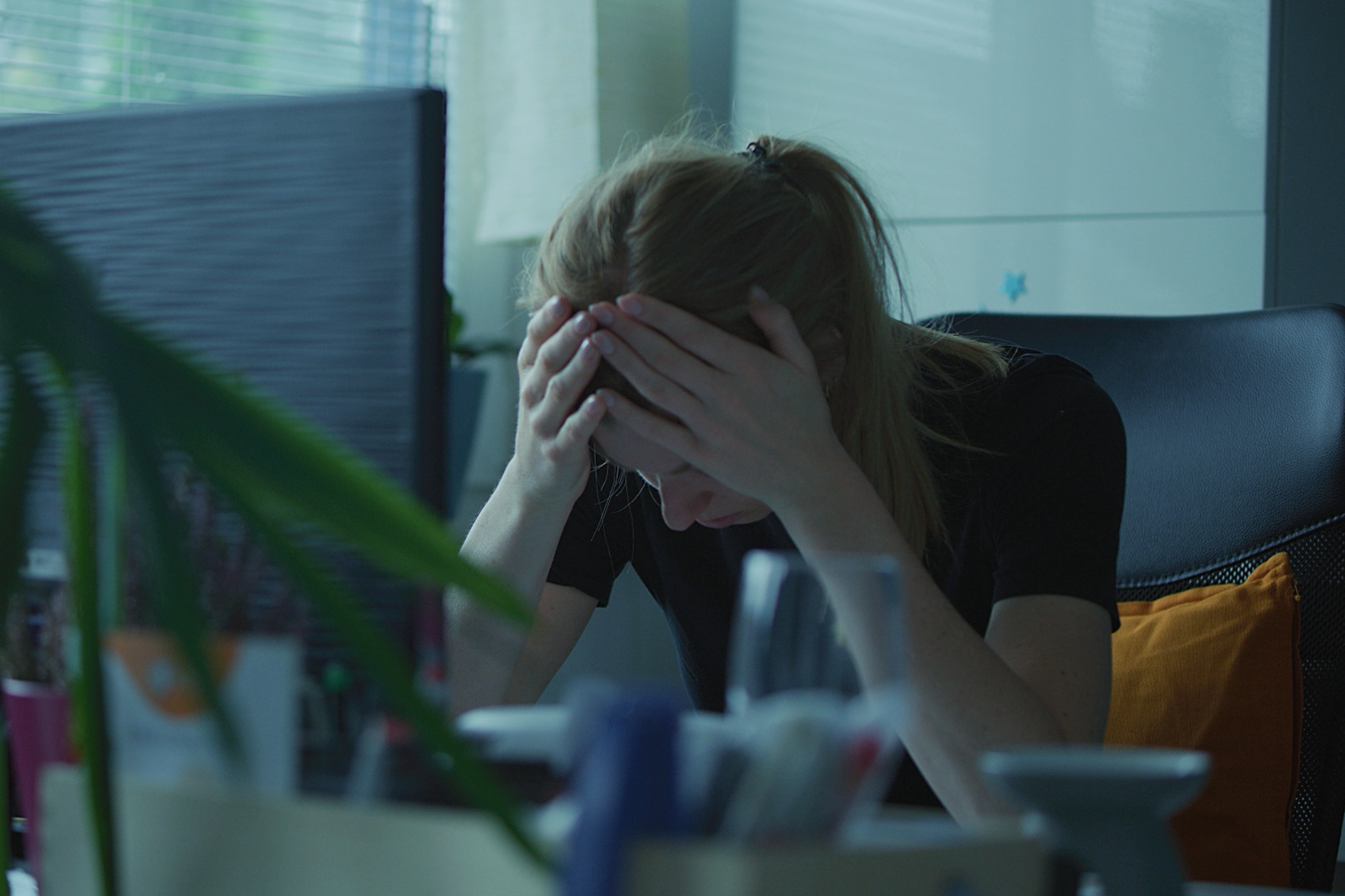 Frau mit gesenkten Kopf an ihrem Schreibtisch im Büro. 